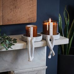 two candles sitting on top of a marble mantle