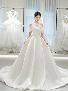 a woman in a white wedding dress standing next to dresses on mannequins