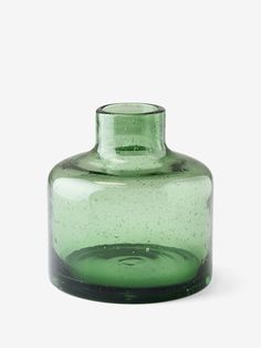 a green glass vase sitting on top of a white table