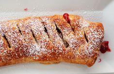 a pastry with powdered sugar and cherries on it