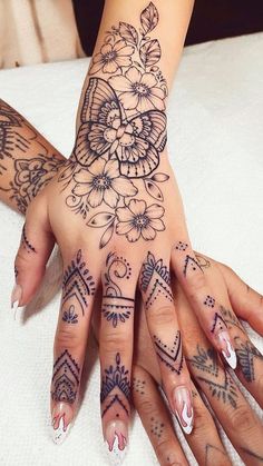 a woman's hands with tattoos and flowers on them