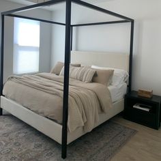 a bedroom with a four post bed and rugs on the floor in front of it