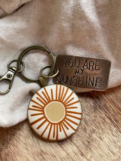 a brown and white keychain with an orange sun on it that says you are my sunshine