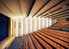 an empty auditorium with rows of orange seats