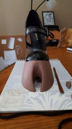 a pair of black shoes sitting on top of a wooden table next to a pencil