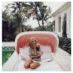 a woman sitting on the ground holding a dog in her lap and smiling at the camera