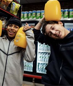 two young men holding up yellow jugs in front of their faces and smiling at the camera