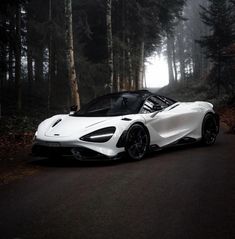 a white sports car parked on the side of a road in front of some trees