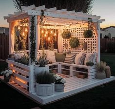 a white gazebo with plants and lights on it