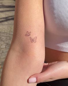 a woman's arm with a small butterfly tattoo on the left side of her arm