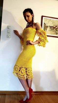 a woman in a yellow crochet dress and red high heels posing for the camera