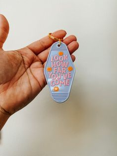 a hand holding a keychain that says look how far you've come