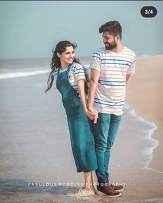 a man and woman walking on the beach holding hands