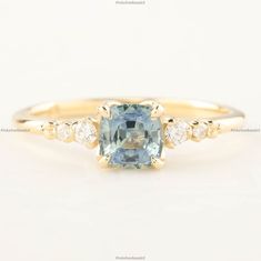 an aqua and white diamond ring with two diamonds on the band, set in yellow gold