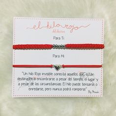 two red string bracelets with silver heart charms on each one and the words el hilo - rojo written in spanish