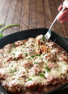 a person is taking a piece of meatball pizza from a pan with a fork