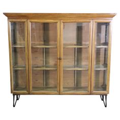 a wooden cabinet with glass doors and metal legs