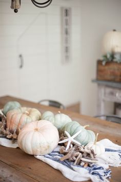 a wooden table topped with lots of different types of pumpkins on top of it