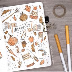 an open notebook with the words november written on it next to pencils and markers