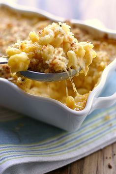 a spoon full of macaroni and cheese being lifted from a casserole dish