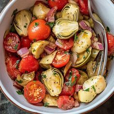 a white bowl filled with lots of different types of veggies next to a fork