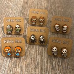 six pairs of cartoon character studs are displayed on a table with brown card holders