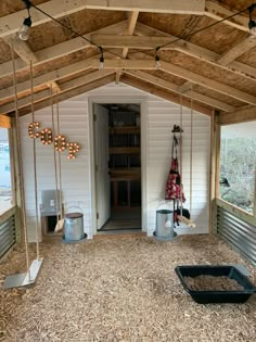 the inside of a shed with swings and wood chips