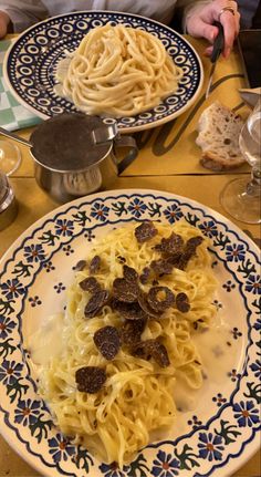 two plates with pasta and meat on them