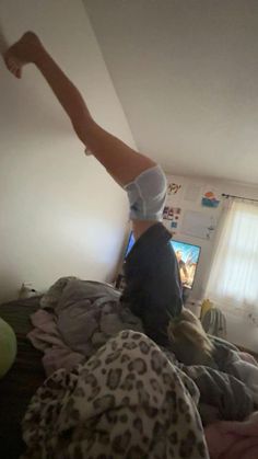 a woman is standing on one leg in the middle of her bed while she's watching tv