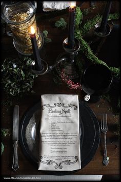 a table set with black plates, silverware and candles for an elegant dinner party