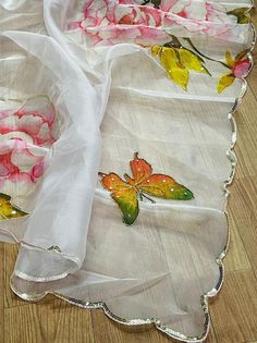 the table is covered with white linens and has butterflies painted on them, along with pink roses