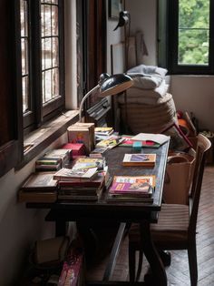 a table with many books on it next to a window