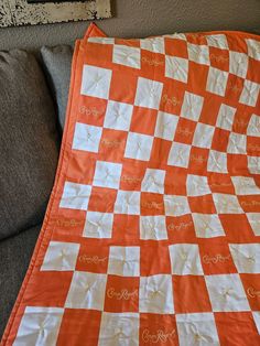 an orange and white checkerboard quilt on a couch with the word love written across it