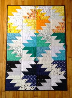 a colorful quilt on the floor with wooden floors