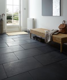 a room with black tile flooring and two benches in front of the door that leads to an outside patio