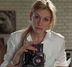 a woman holding up a camera in front of her face and looking at the camera