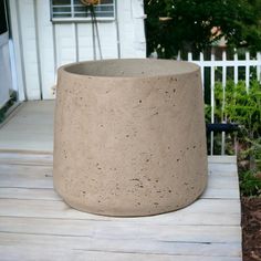 a large cement planter sitting on top of a wooden deck next to a white house