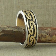 a silver and gold ring sitting on top of a piece of wood