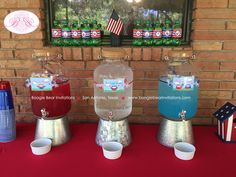 three water jugs are lined up on a red table with american flags in the background