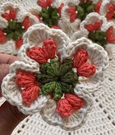 two crocheted flowers are being held by someone's hand