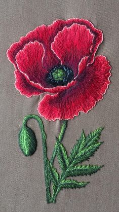 a red flower with green leaves is embroidered onto a gray fabric piece that has been stitched to it