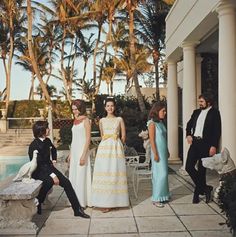 a group of people standing next to each other in front of a pool and palm trees