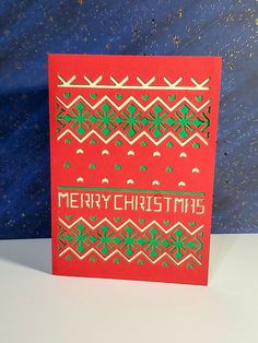 a red christmas card with green and gold designs on the front that says merry christmas