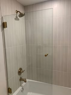 a bath tub sitting inside of a bathroom next to a walk in shower head mounted on a wall