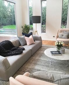 a living room filled with furniture and lots of large windows overlooking the backyard area is shown