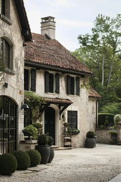 an old stone house with black shutters and potted plants