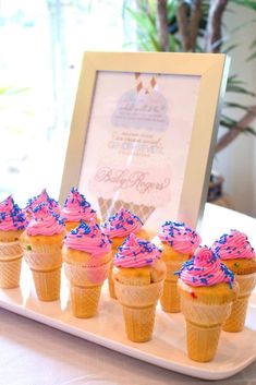 cupcakes with pink frosting and sprinkles on a white tray