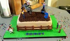 a birthday cake with people riding horses in the dirt and on top of it, surrounded by confetti