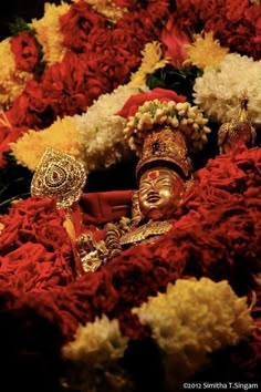 a close up of a statue surrounded by flowers