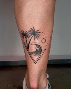 a man's leg with a palm tree and wave tattoo on the lower leg